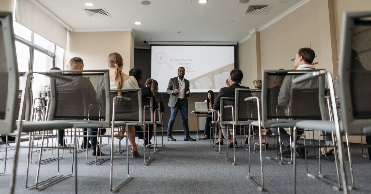Business seminar with a diverse group, featuring a speaker in a modern conference room.
